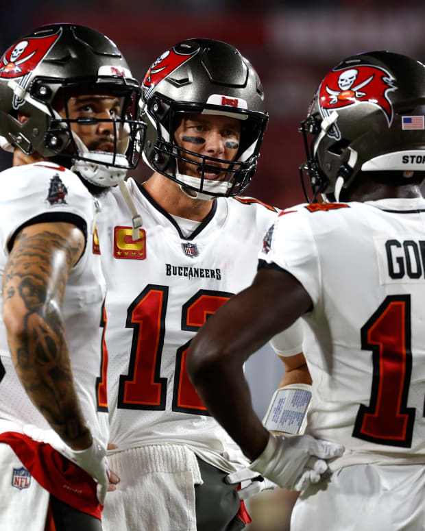 Tampa Bay Buccaneers players Tom Brady (12), Mike Evans (13), and Chris Godwin (14) discuss strategy during a game.