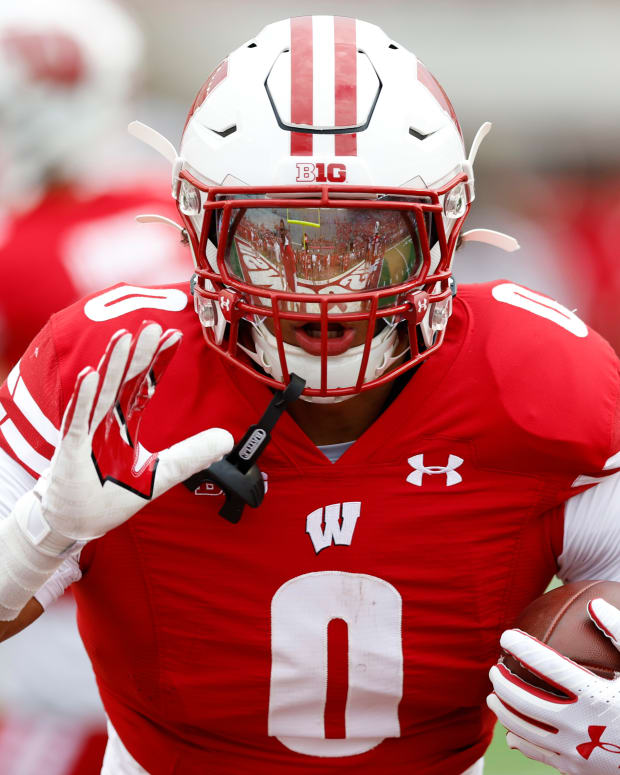 Wisconsin running back Braelon Allen running with the football in warmups with the reflection of his visor shown.