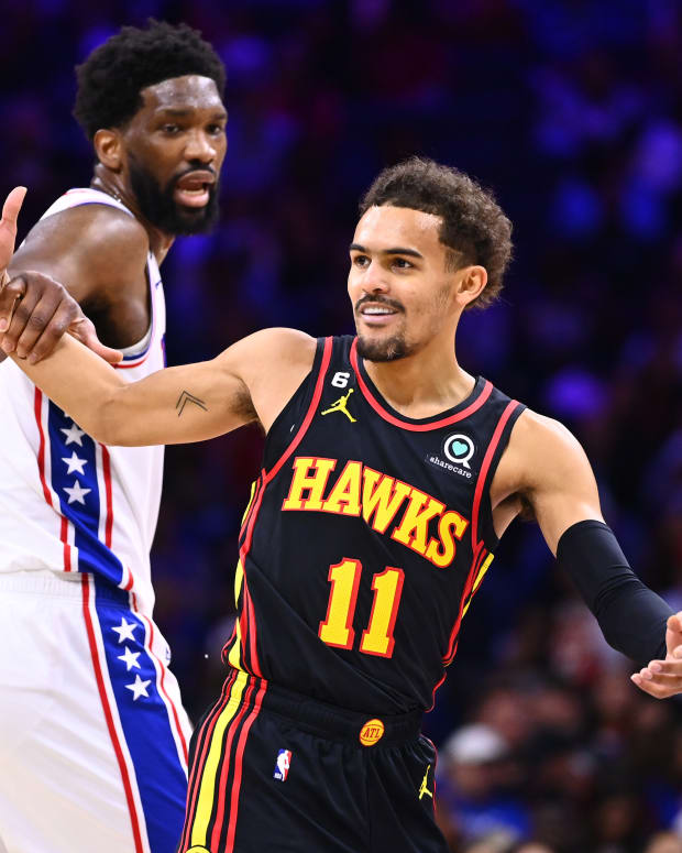 Hawks guard Trae Young reacts as 76ers center Joel Embiid grabs him.