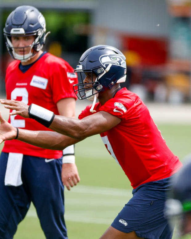 Seattle Seahawks quarterback Geno Smith (7) receives a shotgun snap in front of quarterback Drew Lock (2) during minicamp practice at the Virginia Mason Athletic Center Field.