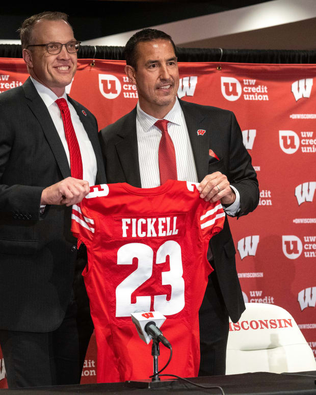 Luke Fickell posing with a Wisconsin jersey during his introductory press conference.