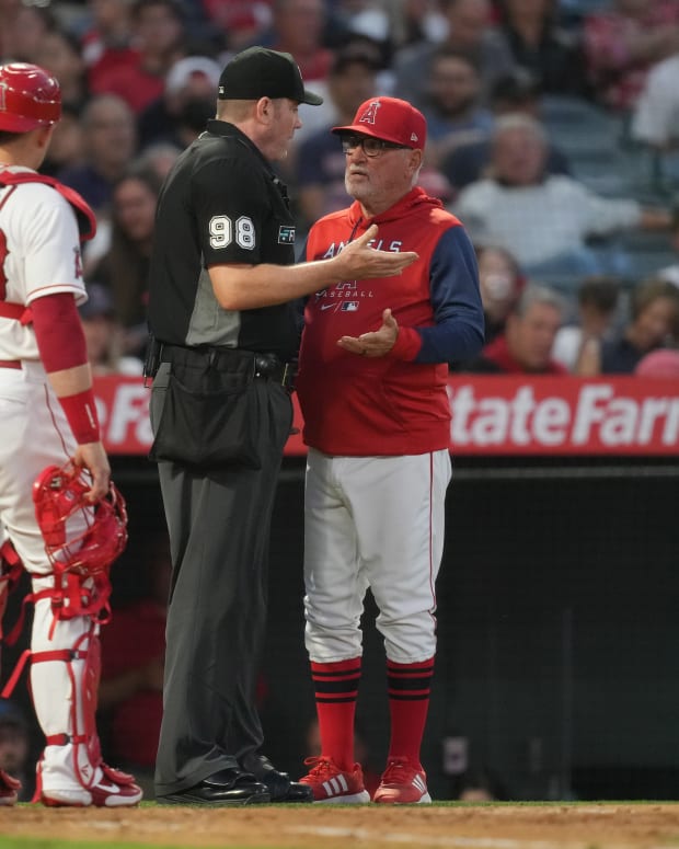 Jun 6, 2022; Anaheim, California, USA; Los Angeles Angels manager Joe Maddon (right) talks with umpire Chris Conroy (98) as catcher Max Stassi (33) watches in the fifth inning against the Boston Red Sox at Angel Stadium. Mandatory Credit: Kirby Lee-USA TODAY Sports