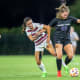 Grace Coppinger (23) tussles with an Aggie defender for the ball.