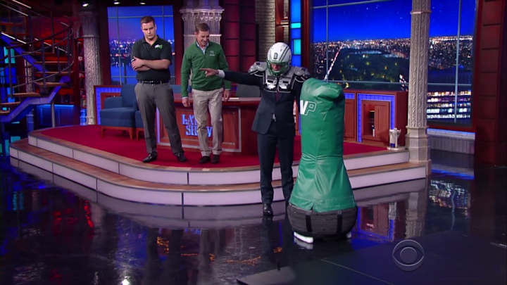 Stephen Colbert practices his tackling form on a robot Stephen Colbert practices his tackling form on a robot