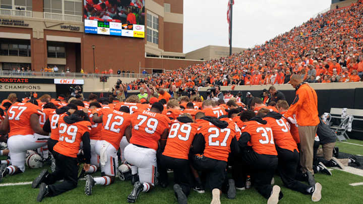 Against a somber backdrop, Oklahoma St defeats Kansas, 58-10