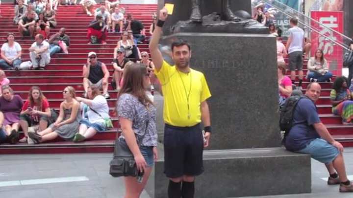 A guy dressed as a referee walked the streets of New York giving people red and yellow cards