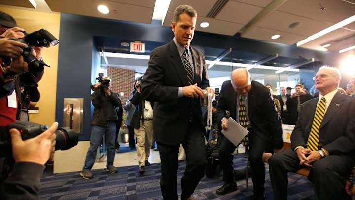 Jim Harbaugh trips on his way to podium at Michigan press conference
