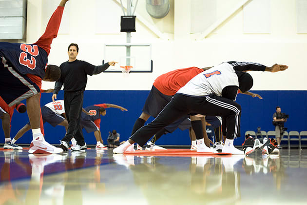 Kent Katich leading a group yoga class of professional basketball players. 