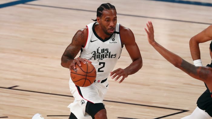 LA Clippers forward Kawhi Leonard brings the ball up court against Denver Nuggets guard Monte Morris