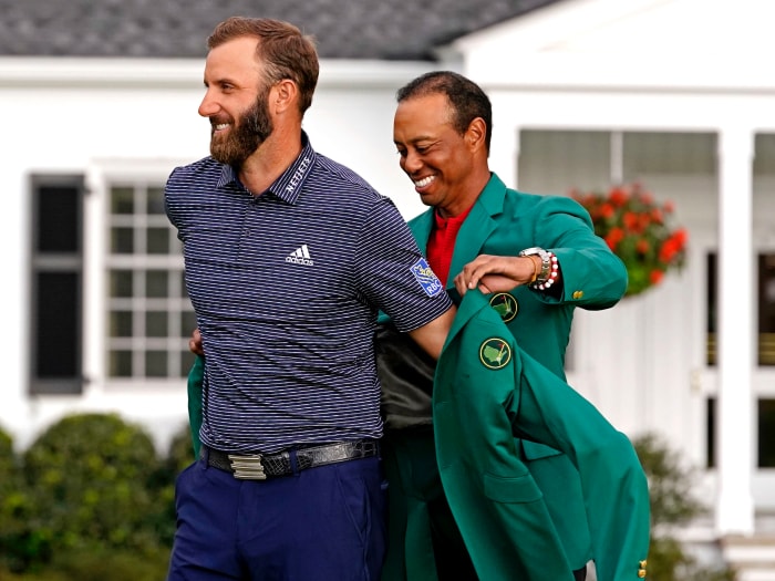 2019 Masters Champion Tiger Woods presents Dustin Johnson with a green jacket after winning The Masters Golf Tournament