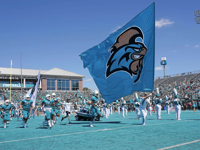 Coastal Carolina carries a school flag onto the field