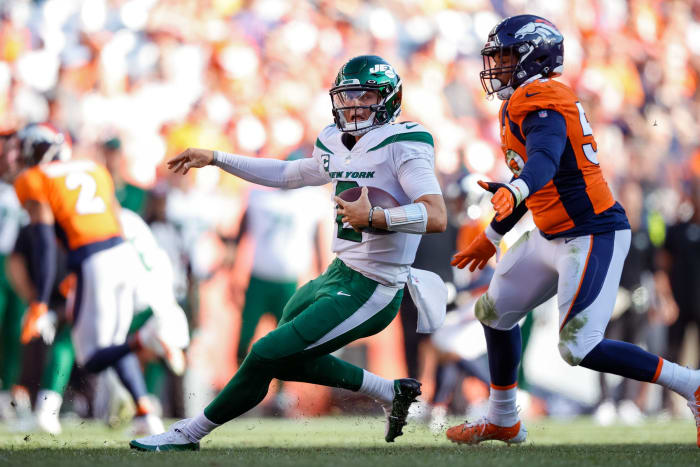 New York Jets quarterback Zach Wilson (2) scrambles in the backfield under pressure from Denver Broncos linebacker Malik Reed (59) in the fourth quarter at Empower Field at Mile High.