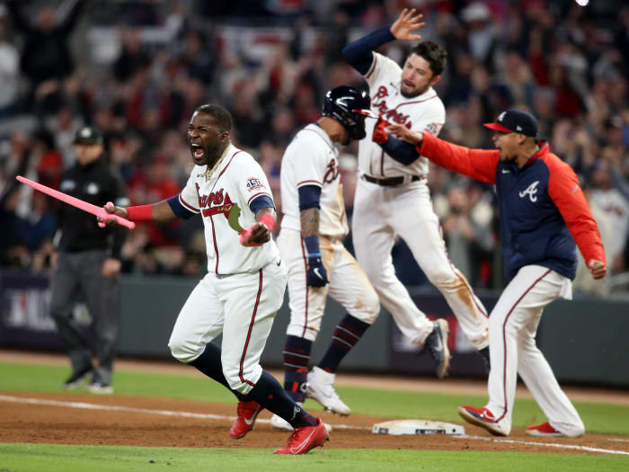 October 17, 2021;  Cumberland, Georgia, United States;  Atlanta Braves center fielder Guillermo Heredia (38) celebrates with toy swords as outfielder Eddie Rosario (8) celebrates his RBI-winning game against the Los Angeles Dodgers during the ninth inning of Game 2 of the NLCS 2021 at Truist Park.