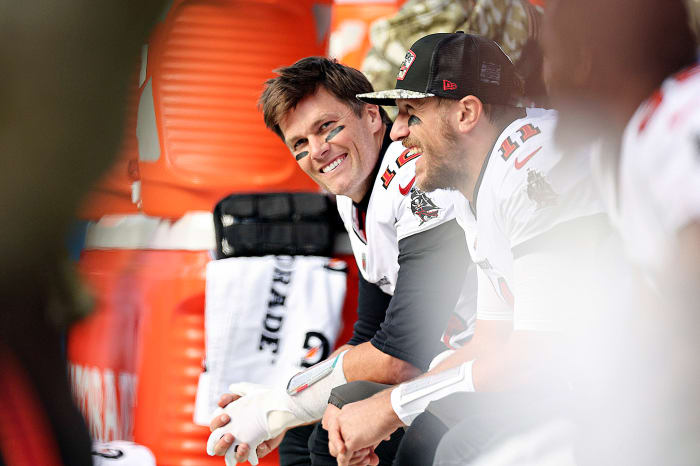 Tom Brady smiles as he looks up from the bench during a Bucs game