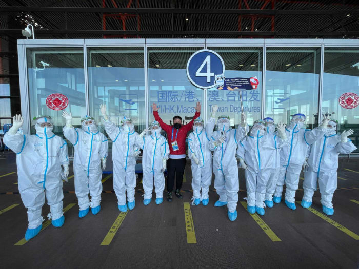 Sports Illustrated photographer Erick W. Rasco poses with workers in hazmat suits.