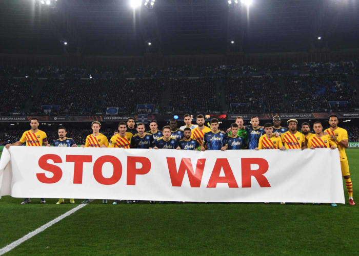 Players of Napoli and Barcelona stand behind a banner which reads: "STOP WAR"
