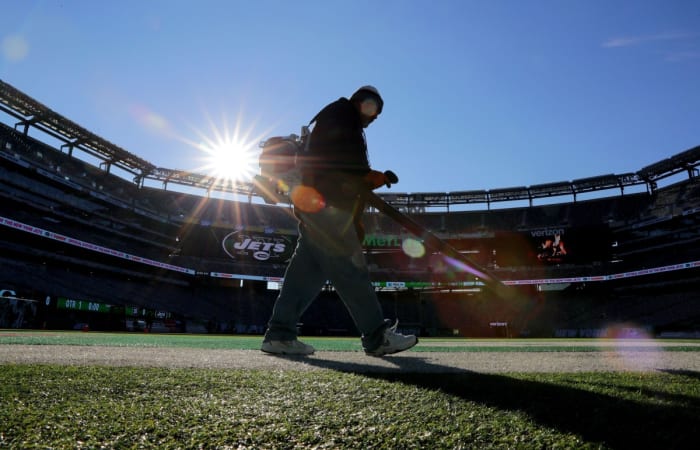 Un membre de l'équipe des terrains des Jets de New York souffle sur le gazon artificiel avant le match des Packers de Green Bay contre les Jets de New York au stade MetLife le dimanche 21 décembre.  23, 2018, à East Rutherford.