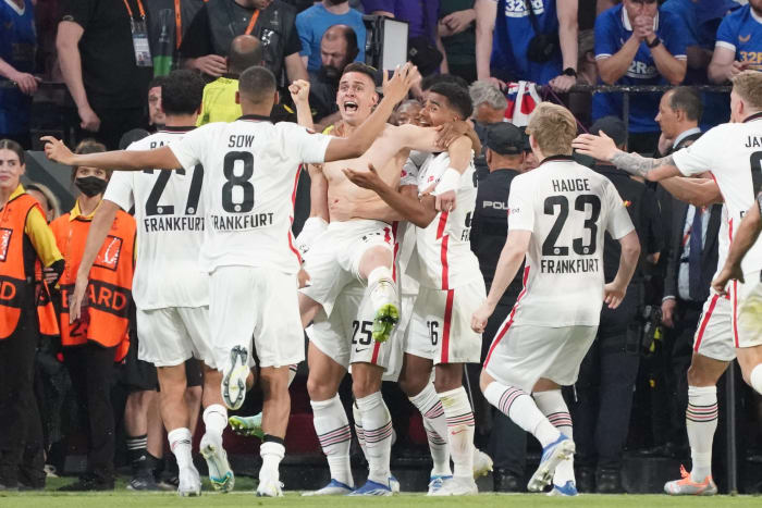 A shirtless Rafael Santos Borre is mobbed by his Frankfurt teammates after scoring the winning spot-kick in his side's penalty-shootout victory over Rangers in the 2022 Europa League final