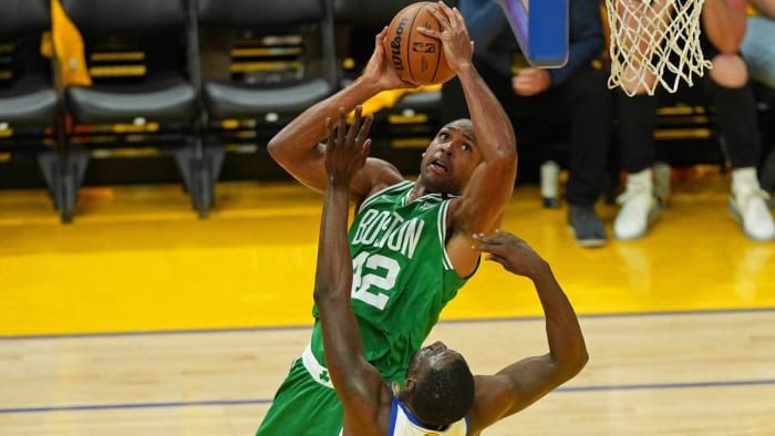 Le centre des Boston Celtics Al Horford (42 ans) tire le ballon contre l'attaquant des Golden State Warriors Draymond Green.
