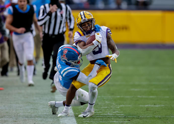 Dec 19, 2020;  Baton Rouge, Louisiana, USA;  LSU Tigers wide receiver Koy Moore (5) is tackled going out of bounds by Mississippi Rebels defensive back Jon Haynes (5) at Tiger Stadium.  Mandatory Credit: Stephen Lew-USA TODAY Sports