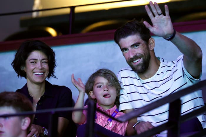 Michael Phelps and his son Boomer, along with his wife Nicole, wave to the crowd from the stands during the 2021 US Olympic Trials in Omaha.