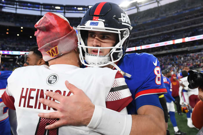 Washington Commanders quarterback Taylor Heinicke and New York Giants quarterback Daniel Jones embrace on the field