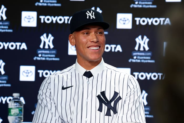 Aaron Judge smiles at a press conference in a Yankees uniform and hat