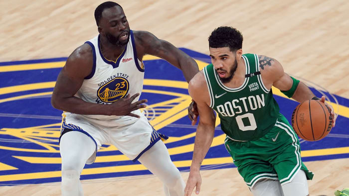 Boston Celtics striker Jason Tatum (0) controls the ball against Golden State Warriors striker Draymond Green.