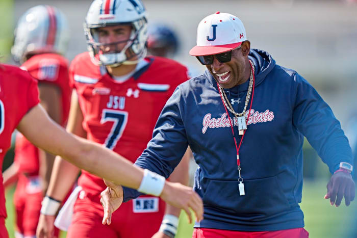Deion Sanders laughs and shakes a player's hand during a Jackson State practice