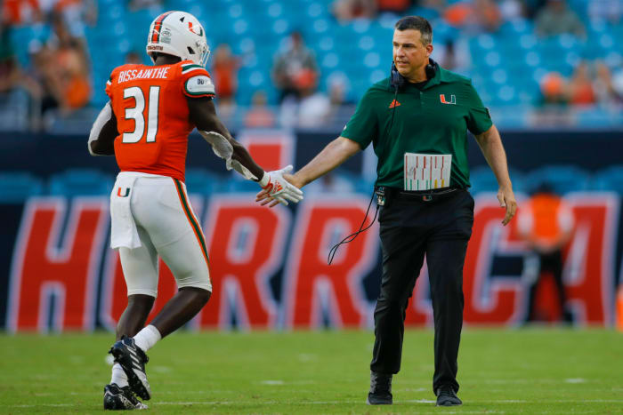 Mario Cristobal high fives Miami player as he walks off field.