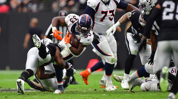 Broncos running back Javonte Williams (33) is brought down by Raiders linebacker Denzel Perryman (52) during the first half at Allegiant Stadium.