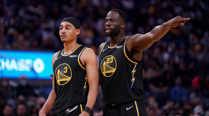 Warriors forward Draymond Green and guard Jordan Poole stand next to each other during a game.