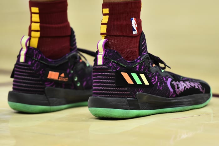 Black, purple, and green Adidas 'Dame 7' shoes.