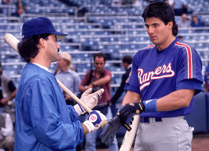Rafael Palmeiro and Jose Canseco talk before a Rangers game.