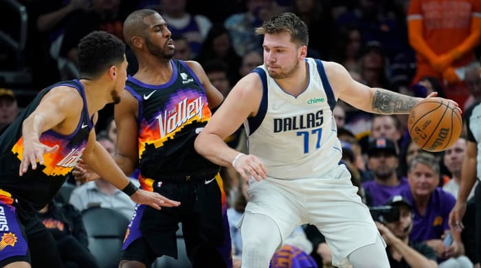 Dallas Mavericks guard Luka Doncic (77) works the ball to the basket against Phoenix Suns guard Chris Paul, center, and Phoenix Suns guard Devin Booker, left, during the second half of Game 1 in the second round of the NBA Western Conference playoff series Monday, May 2, 2022, in Phoenix.