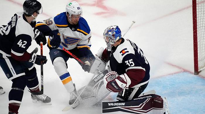 St. Louis Blues left wing Pavel Buchnevich, center, has his shot stopped by Colorado Avalanche goaltender Darcy Kuemper, right, after he was shot in the first period of an NHL hockey game Tuesday, April 26, 2022, in Denver passed defender Josh Manson.