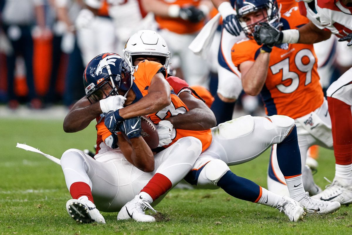 Arizona Cardinals linebacker Vontarrius Dora (54) tackles Denver Broncos running back Khalfani Muhammad (33) in the first quarter at Broncos Stadium at Mile High.