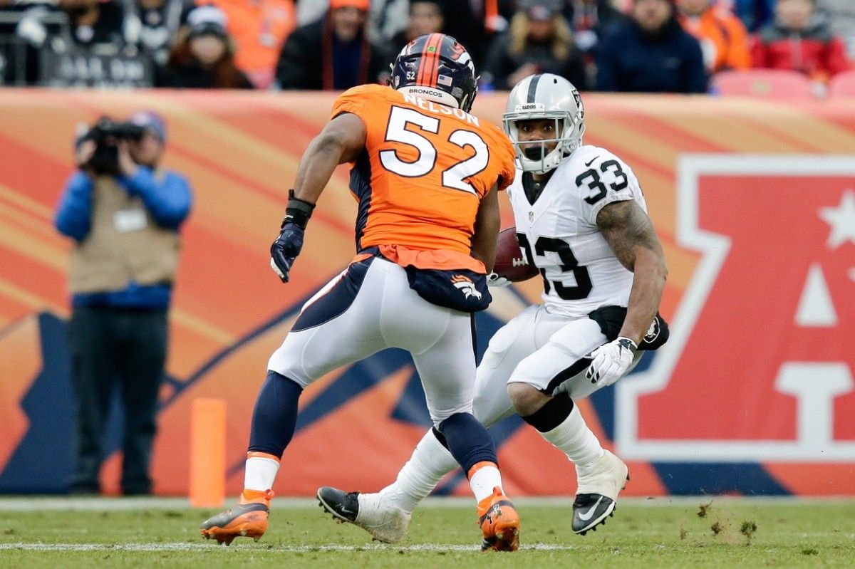 Oakland Raiders running back DeAndre Washington (33) runs the ball as Denver Broncos inside linebacker Corey Nelson (52) defends in the second quarter at Sports Authority Field at Mile High.