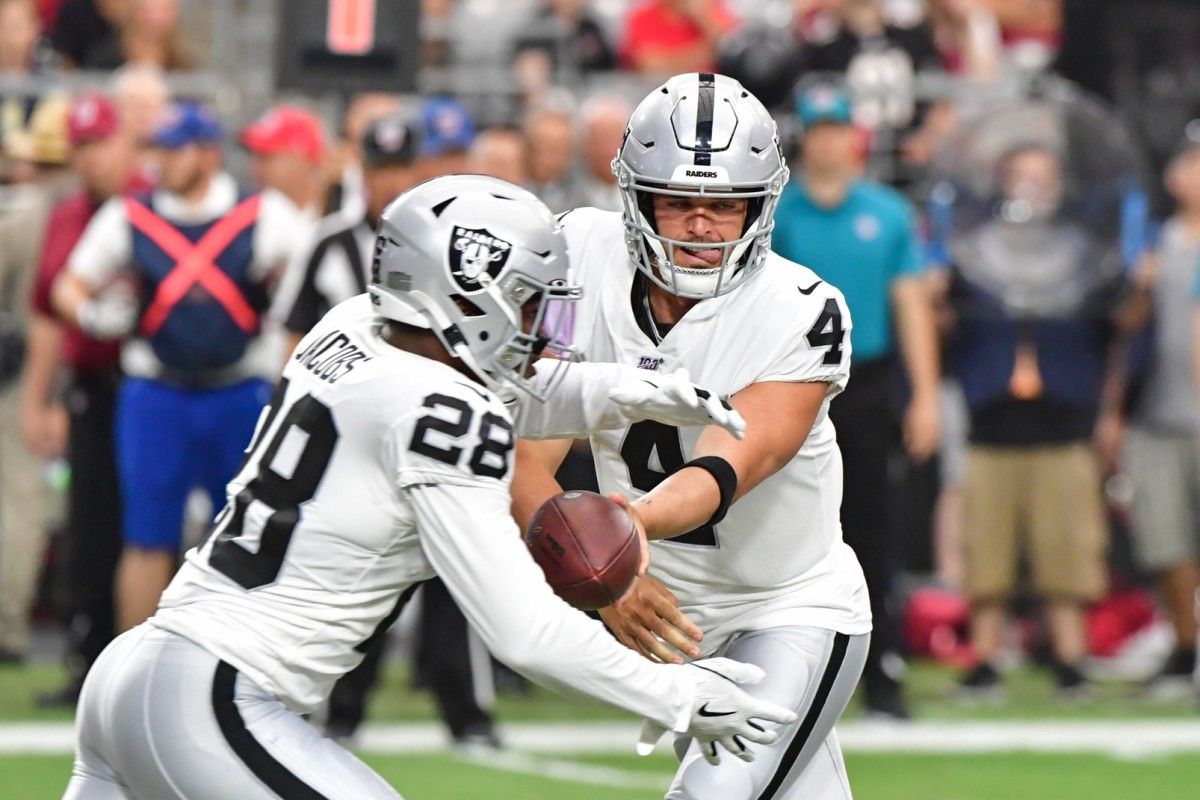 Oakland Raiders quarterback Derek Carr (4) hands off to running back Josh Jacobs (28) against the Arizona Cardinals during the first half during a preseason game at State Farm Stadium.