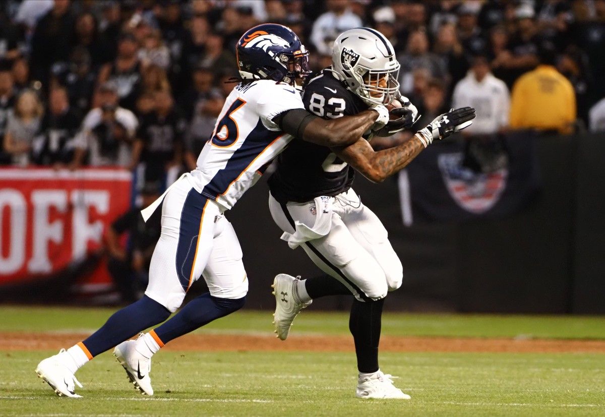 Oakland Raiders tight end Darren Waller (83) carries the ball against Denver Broncos cornerback Isaac Yiadom (26) during the first quarter at Oakland Coliseum.