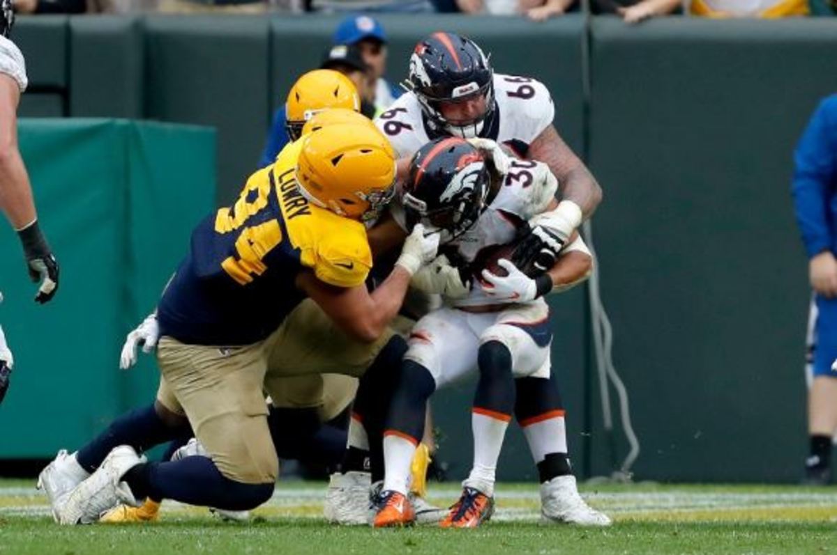 Denver Broncos running back Phillip Lindsay (30) fights his way past Green Bay Packers defensive end Dean Lowry (94) for a touchdown with the help of teammate offensive tackle Dalton Risner during the second half of an NFL football game Sunday, Sept. 22, 2019, in Green Bay, Wis.
