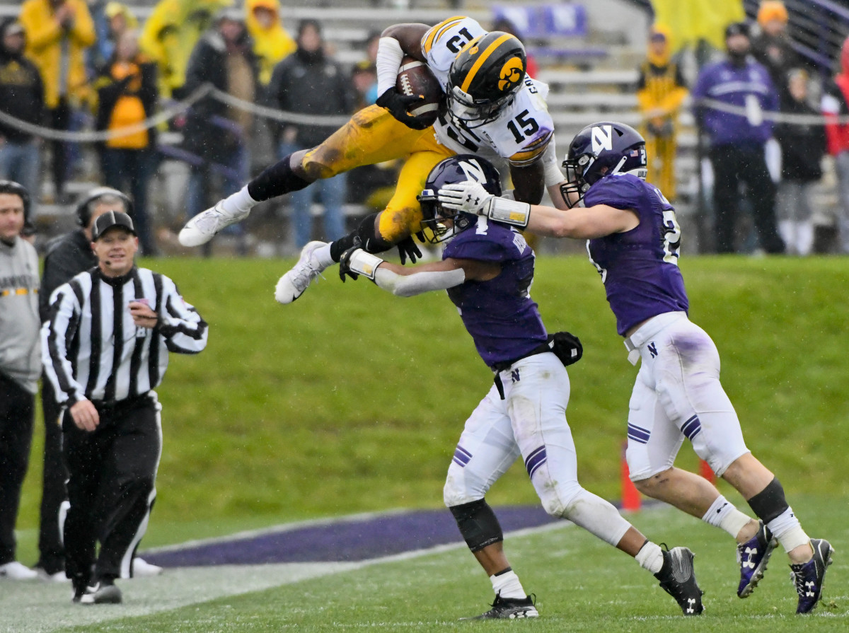 Iowa running back Tyler Goodson (15) leaps over Northwestern defensive back Greg Newsome II (2) and linebacker Chris Bergin (28) during the second half of Saturday's game.