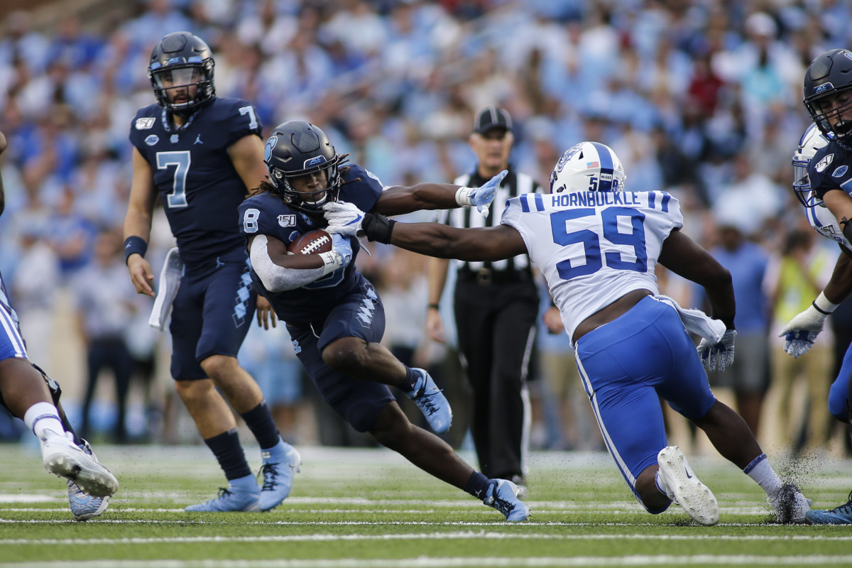 Michael Carter gains yardage as Duke's Tre Hornbuckle tries to make a tackle 