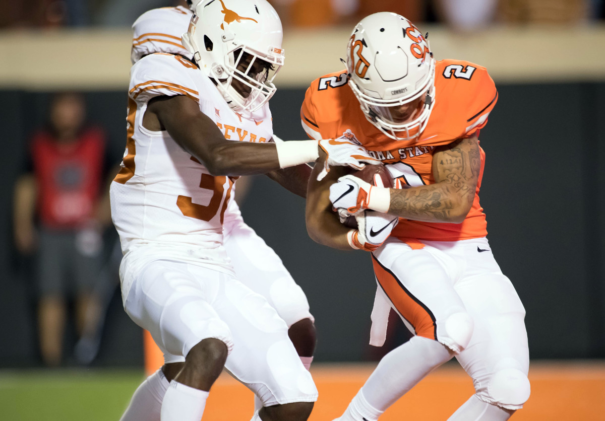 Tylan Wallace scores a touchdown while defended by Texas Longhorns defensive back DeMarvion Overshown (31) during the first quarter at Boone Pickens Stadium.