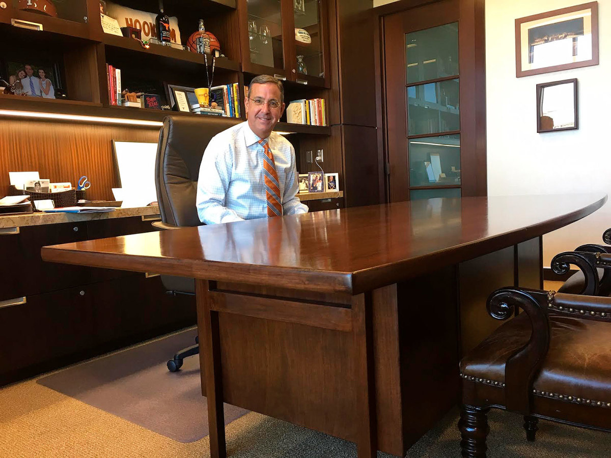 Texas athletic director Chris Del Conte smiles from behind his office desk, the same one used by Darrell Royal around 60 years ago.