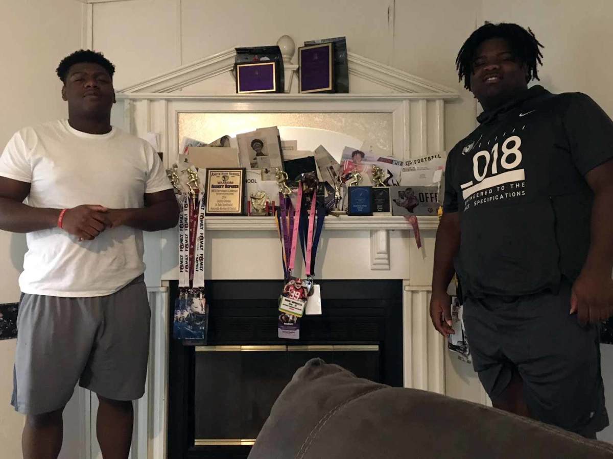Five-star defensive tackle Ishmael Sopsher (right) and his brother Rodney pose on either side of the family’s mantle overflowing with athletic memorabilia at the Sopshers’ home in Amite, La.