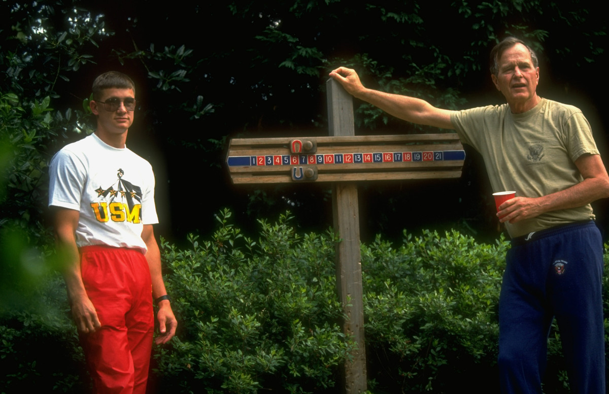 Bush leans on a horseshoe pitching post while hosting Desert Storm troops at the White House in 1991.