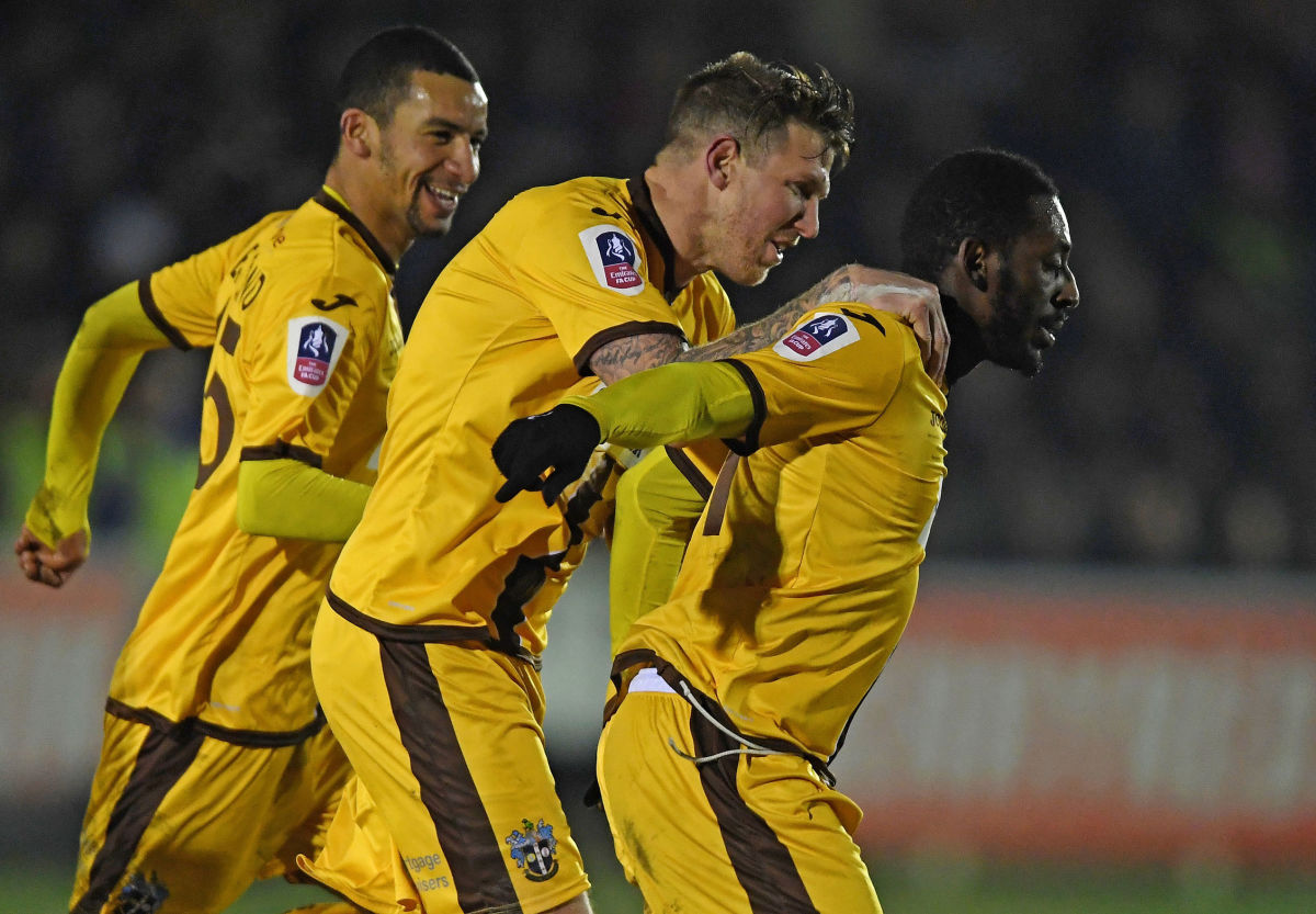 KINGSTON UPON THAMES, ENGLAND - JANUARY 17: Roarie Deacon of Sutton United (R) celebrates scoring his sides first goal with his Sutton United team mates during the Emirates FA Cup third round replay between AFC Wimbledon and Sutton United at The Cherry Red Records Stadium on January 17, 2017 in Kingston upon Thames, England.  (Photo by Mike Hewitt/Getty Images)
