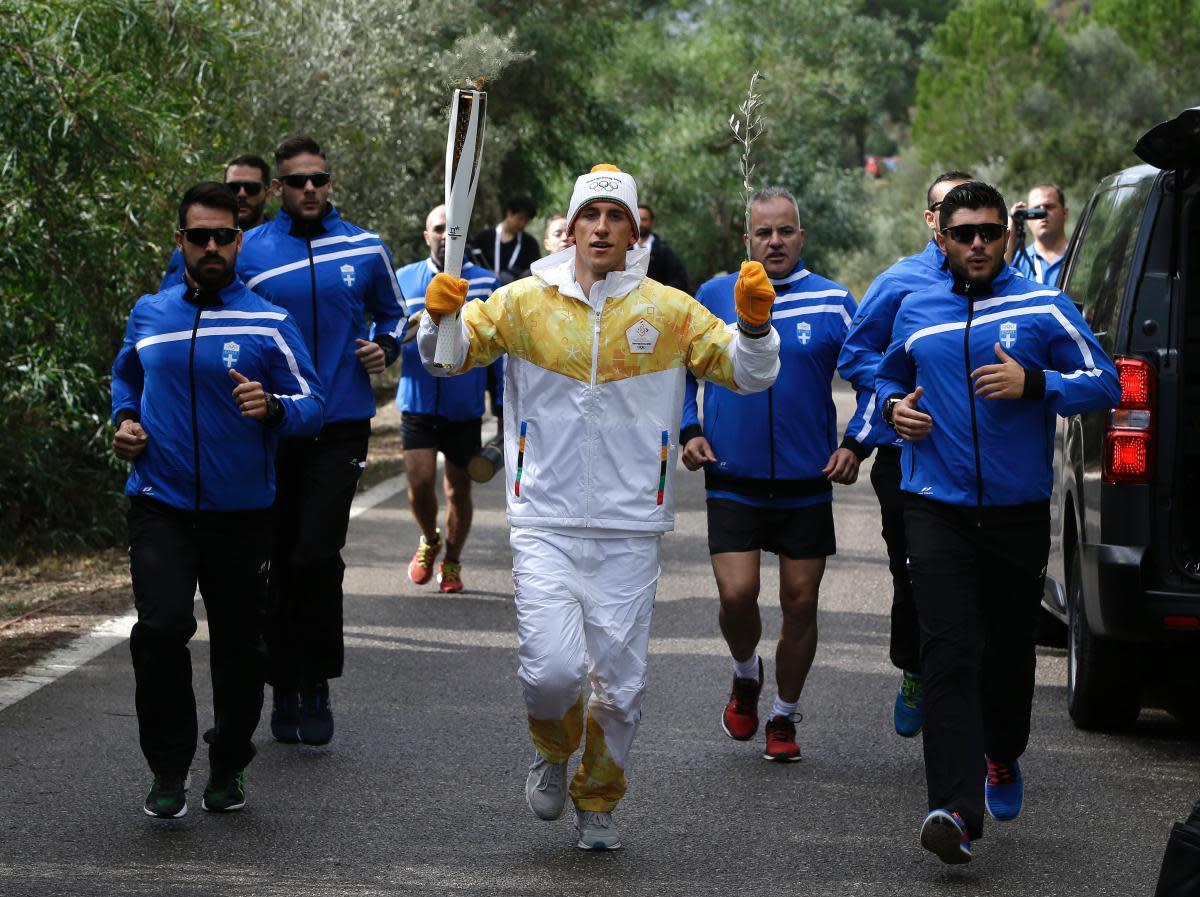 Torch bearer Greek cross-country skier Apostolos Angelis runs with the Olympic flame during the lighting ceremony of the Olympic flame in Ancient Olympia, southwestern Greece, on Tuesday, Oct. 24, 2017. The flame will be transported by torch relay to Pyeongchang, South Korea, which will host the Feb. 9-25, 2018 Winter Olympics. (AP Photo/Thanassis Stavrakis)