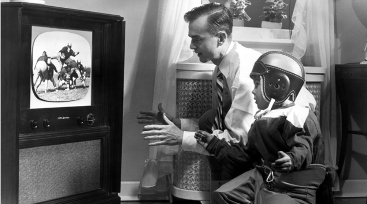 A father and son watching football circa 1955.